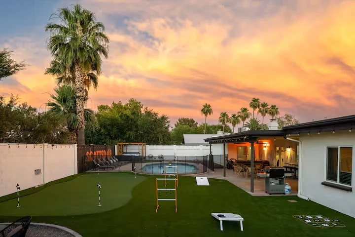Backyard putting green and lawn games at sunset
