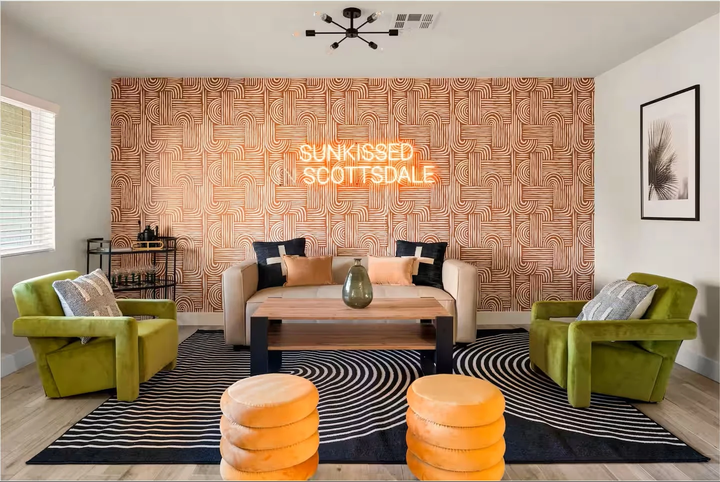 Living room with Sunkissed in Scottsdale neon sign and green velvet chairs