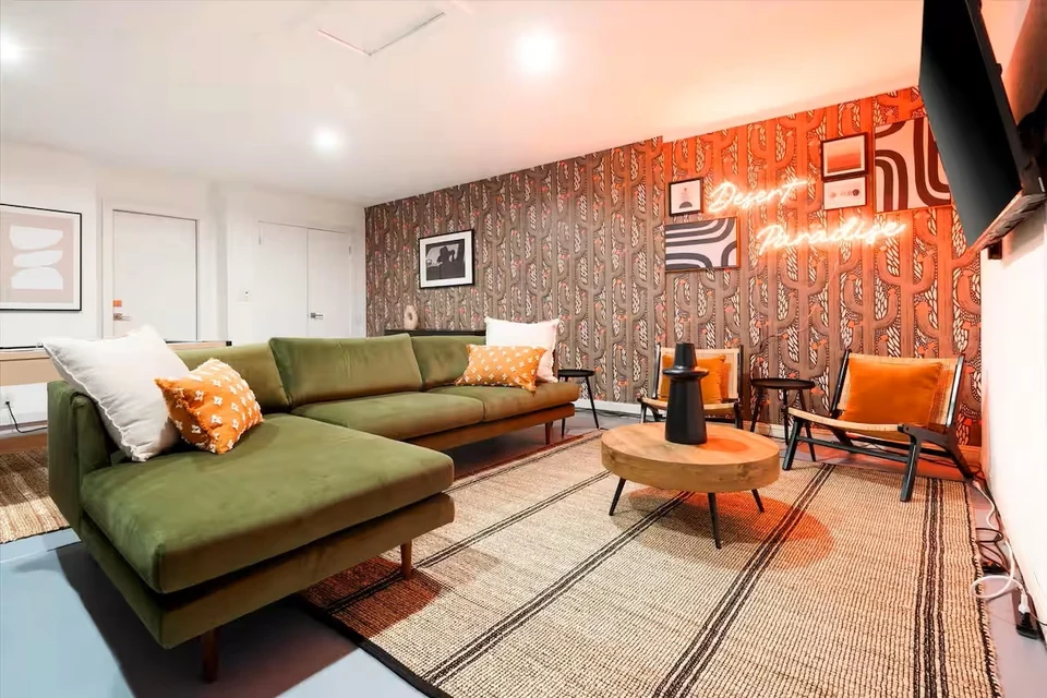 Den with green sectional and Desert Paradise neon sign